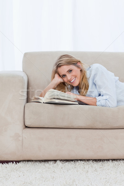 Femme souriante regarder caméra canapé livre heureux [[stock_photo]] © wavebreak_media