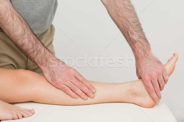 Stock photo: Physiotherapist touching the calf and the foot of a patient in a room
