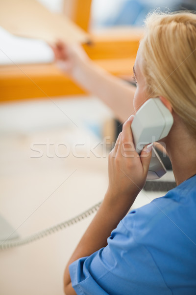 Nurse holding a phone and giving a folder at hospital reception Stock photo © wavebreak_media