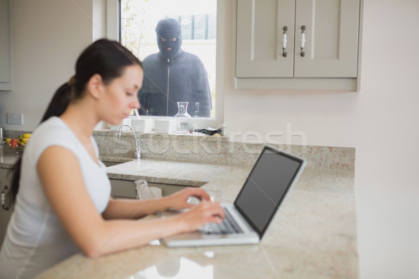 Burglar observing woman working on a laptop in the kitchen Stock photo © wavebreak_media