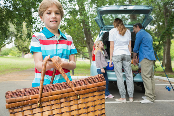 Boy with picnic basket while family in background at car trunk Stock photo © wavebreak_media