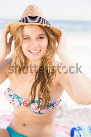 Pretty blonde sitting on the beach applying suncream Stock photo © wavebreak_media