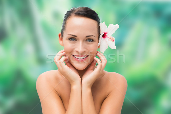 Beautiful nude brunette smiling at camera with flower in her hai Stock photo © wavebreak_media
