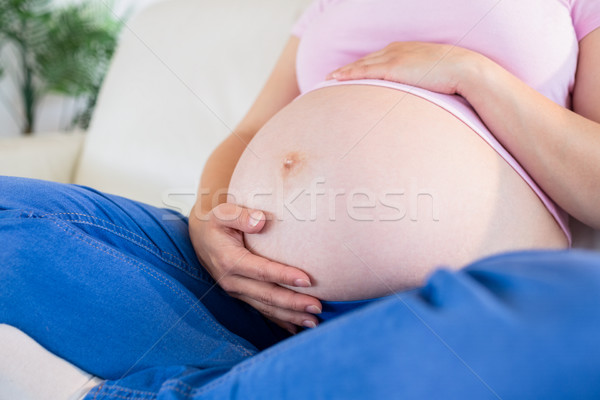 Stock fotó: Közelkép · terhes · nő · ül · kanapé · megérint · has