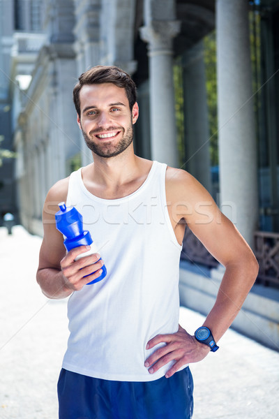 Smiling handsome athlete holding bottle Stock photo © wavebreak_media