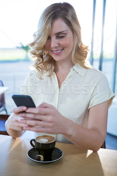 Woman using mobile phone with cup of coffee in table Stock photo © wavebreak_media