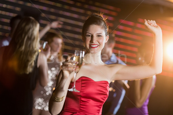 Portrait of young woman holding a glass of champagne while dancing Stock photo © wavebreak_media
