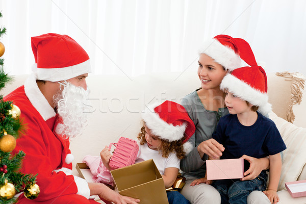 Santa giving presents to his children in the living room with their mother Stock photo © wavebreak_media