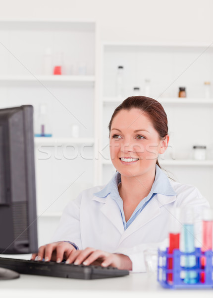 Smiling scientist typing a report with her computer Stock photo © wavebreak_media