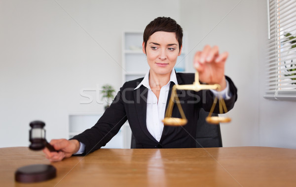 Stock photo: Young woman with a gavel and the justice scale in her office