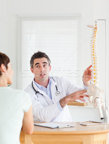 Male Doctor showing a female patient a part of a spine in a room Stock photo © wavebreak_media