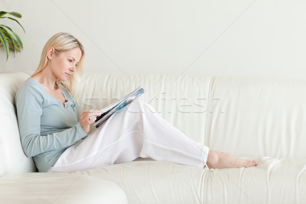 Foto stock: Vista · lateral · mulher · jovem · olhando · catálogo · sofá · relaxar