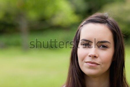Young relaxed woman standing upright in a parkland while looking at the camera Stock photo © wavebreak_media