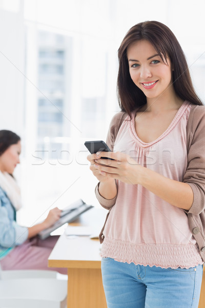 Stock photo: Portrait of a smiling casual young woman text messaging