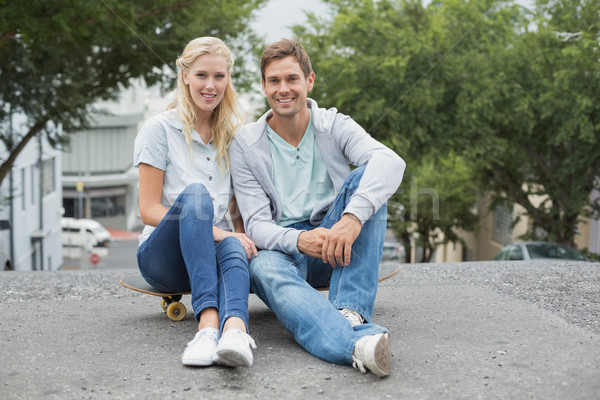 Hip young couple sitting on skateboard smiling at camera Stock photo © wavebreak_media