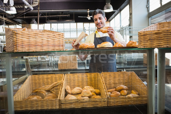 Smiling waiter in apron choosing bread  Stock photo © wavebreak_media