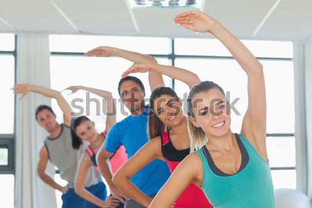 Happy friends practicing tree pose in fitness studio Stock photo © wavebreak_media