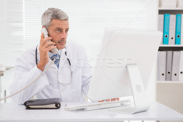 Doctor phoning and using computer  Stock photo © wavebreak_media