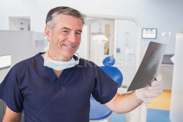 Stock photo: Smiling dentist examining a x-ray 