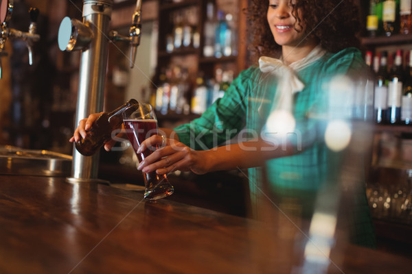 Waitress pouring beer in pilsner glass at counter Stock photo © wavebreak_media
