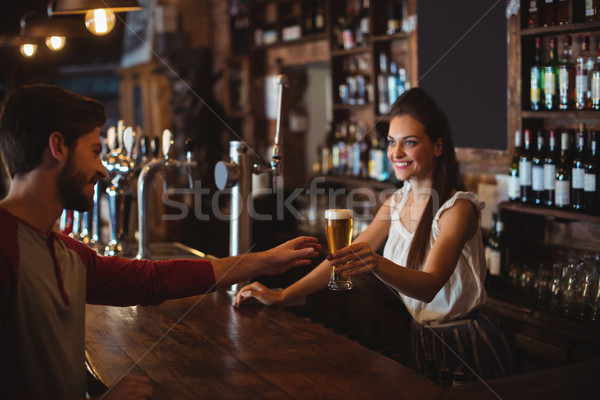 Female bar tender giving glass of beer to customer Stock photo © wavebreak_media