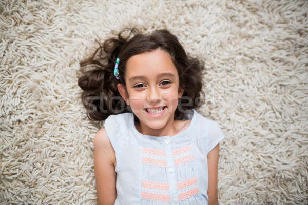 Portrait of smiling girl lying on rug in living room Stock photo © wavebreak_media