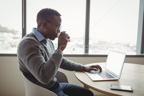 Attentive executive drinking coffee while using laptop Stock photo © wavebreak_media