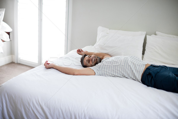 Man lying on bed with arms up on bed Stock photo © wavebreak_media