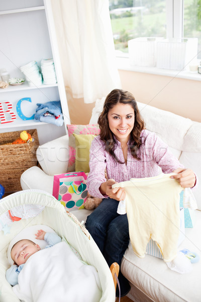 Joyful woman sitting on the sofa with bags reading a card while her baby is sleeping in his cradle Stock photo © wavebreak_media