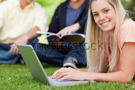 Close-up of a girl using a netbook while lying in a park with friends in background Stock photo © wavebreak_media