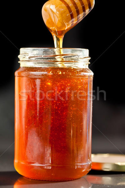 Honey sticky trickle dropping in a jar against a black background Stock photo © wavebreak_media