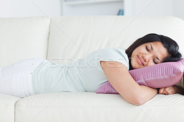 Stock photo: Woman sleeping on a white sofa and holding a pillow in a living room