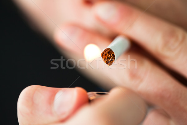 Close up of a man lighting a cigarette against a black background Stock photo © wavebreak_media