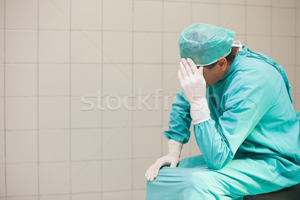 Thoughtful surgeon sitting in a operating room with his hand on head Stock photo © wavebreak_media