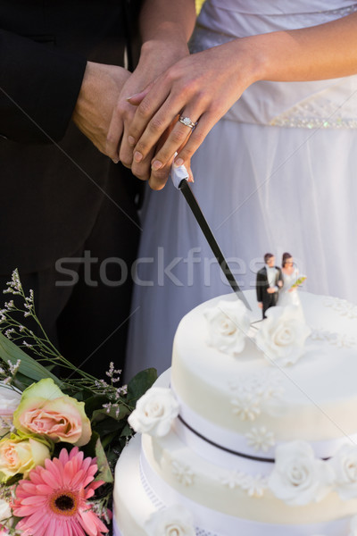 Stock photo: Mid section of newlywed cutting wedding cake