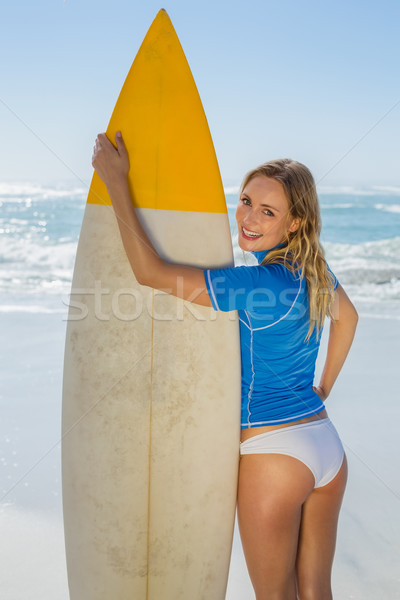 Stock photo: Blonde smiling surfer holding her board on the beach 