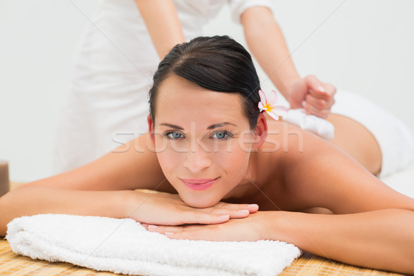Peaceful brunette enjoying a herbal compress massage smiling at  Stock photo © wavebreak_media