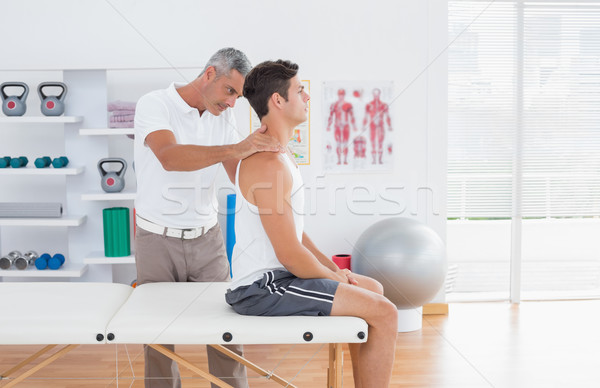 Doctor examining his patient neck  Stock photo © wavebreak_media