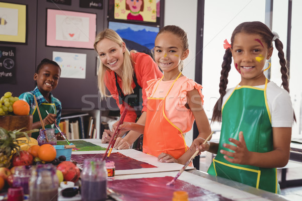 Stock photo: smiling teacher and schoolkids standing in drawing classroom