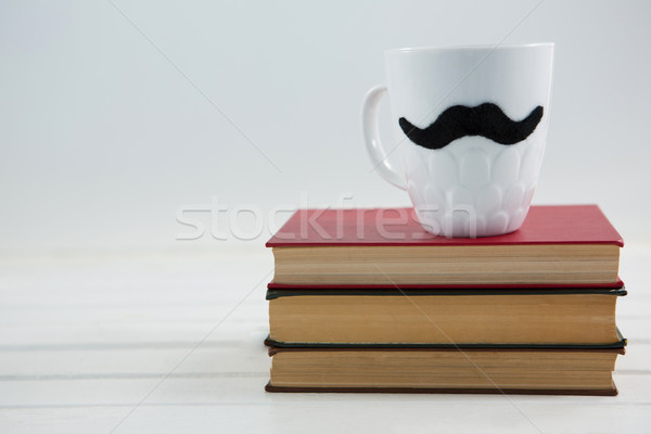 Close up of mug with mustache on books Stock photo © wavebreak_media