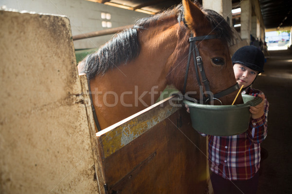 Stock photo: Girl feeding the horse in the stable