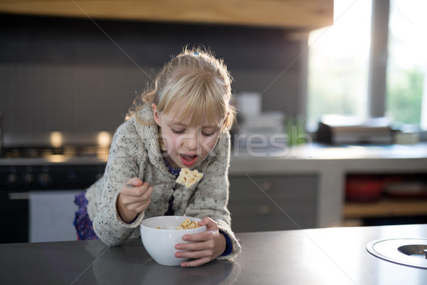 Little girl eating cereals rings with spoon from a bowl Stock photo © wavebreak_media