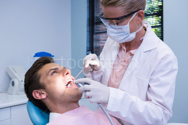 Dentist holding medical equipment while giving treatment to patient Stock photo © wavebreak_media