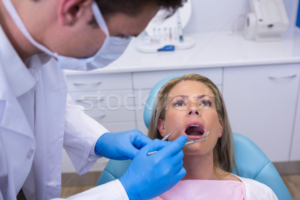 Dentist holding tools while examining woman at medical clinic Stock photo © wavebreak_media