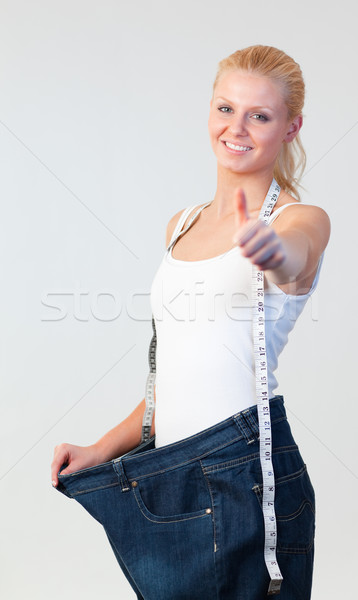 Attractive woman with thumb up wearing big jeans  focus on woman  Stock photo © wavebreak_media