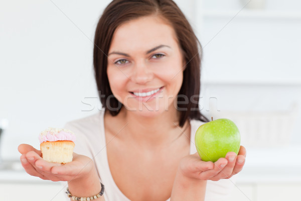 Stock photo: Close up of a cute woman with an apple and a piece of cake looking at the camera