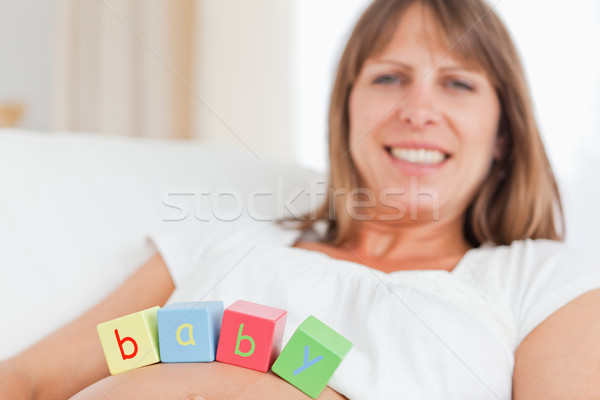 Cute pregnant woman playing with wooden blocks while lying on a sofa in her living room Stock photo © wavebreak_media