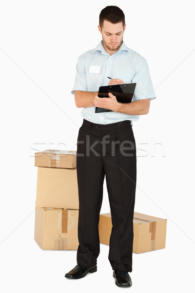 Young post employee with parcels taking notes on his clipboard against a white background Stock photo © wavebreak_media