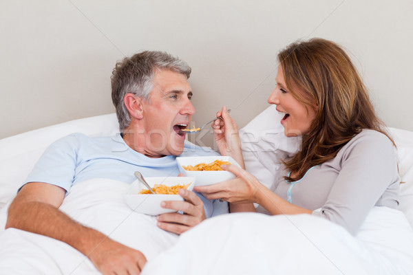 Stock photo: Mature couple eating cereals in their bed