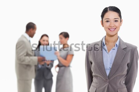 Businesswoman smiling with co-workers watching a laptop in the background Stock photo © wavebreak_media